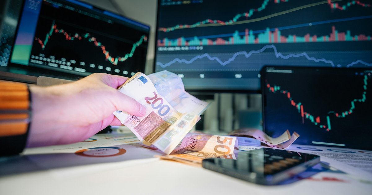 A person holding money in front of a computer screen